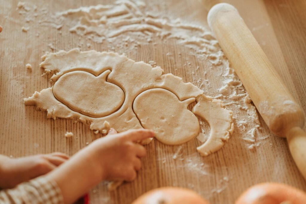 A child making pumpkin-shaped cookies with dough.